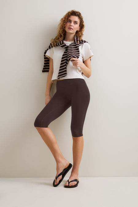 Woman wearing a white t-shirt, brown capri pants, and a striped rugby polo