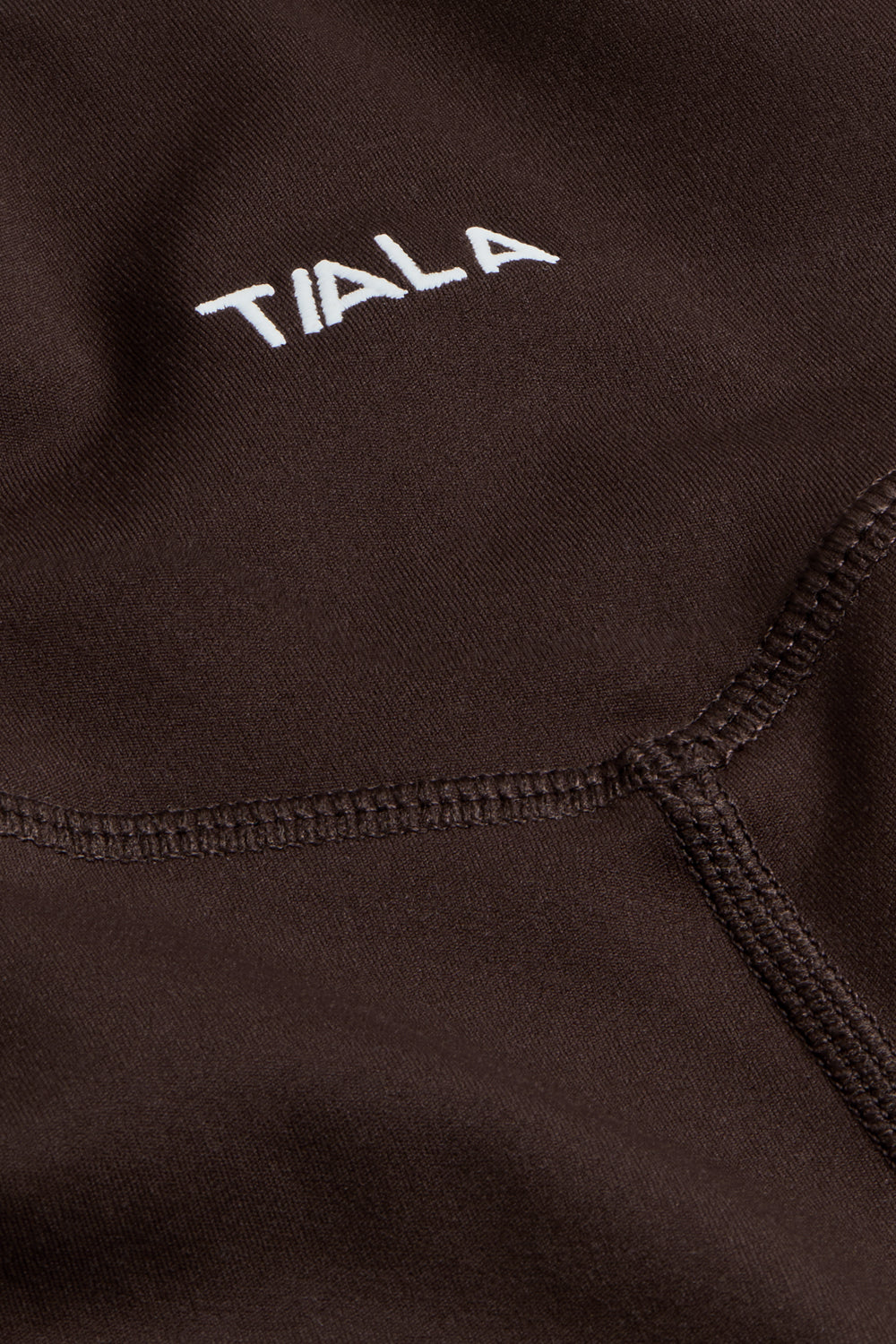 Close-up of a dark brown fabric with 'TIALA' embroidered in white.